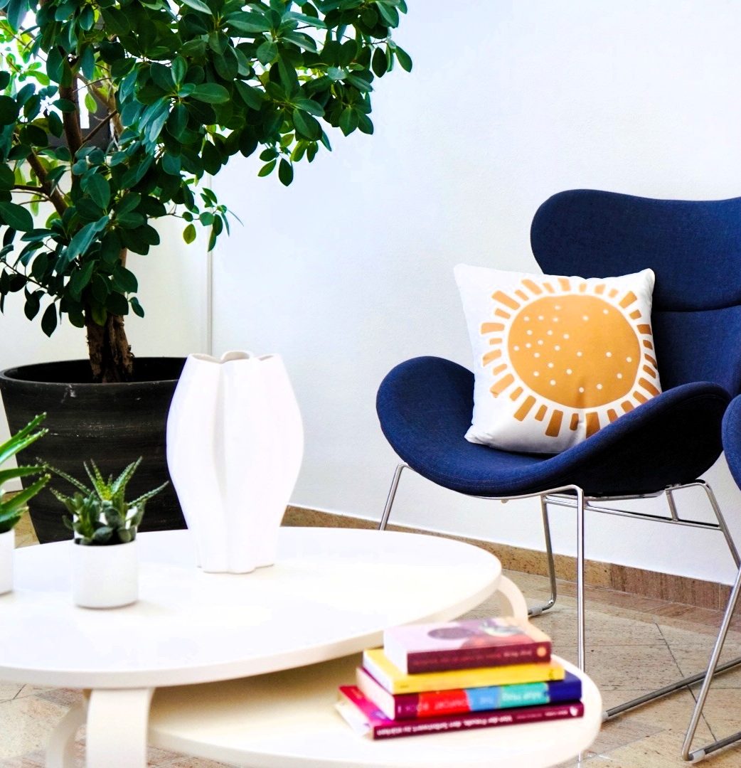 Moderne Wohnzimmereinrichtung mit blauer Couch, Kissen und Pflanzen.
